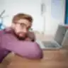 Vyras su akiniais prie nešiojamo kompiuterio