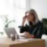 Moteris su akiniais žiūri į kompiuterį